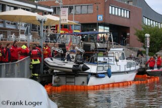 Im Hafen von Leer pumpt die Feuerwehr Wasser aus einem Motorboot und legt eine Ölsperre aus.