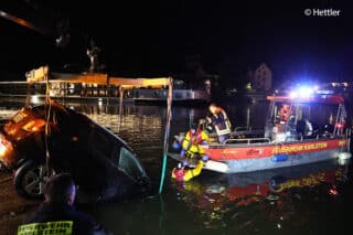 Um den Pkw aus dem Main zu ziehen, müssen Feuerwehrleute Gurte unter den im Wasser befindlichen Rädern anbringen. Foto: Ralf Hettler