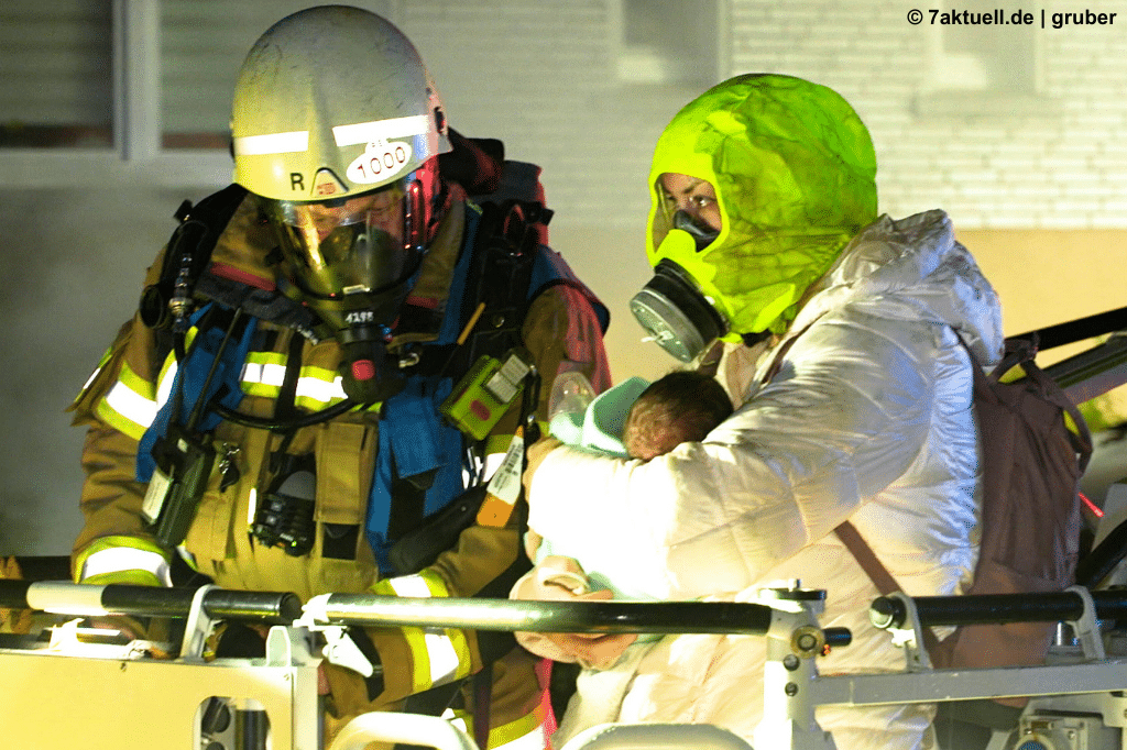 Feuerwehrmann, Mutter und Baby im Drehleiterkorb auf dem Weg nach unten.