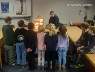 Drittklässler der Grundschule Harpstedt lernen anhand eines Modells, wie sich Rauch in einem Haus ausbreitet. Foto: Feuerwehr Harpstedt